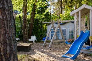 a playground with a slide and a play house at Domki Na Brackiej in Pobierowo