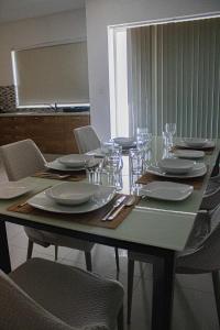 a table with chairs and plates and glasses on it at Modern 3 bedroom with AC apartment in Żabbar