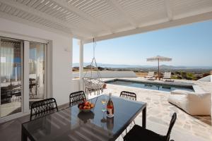 a dining room with a table and chairs and a pool at Villa THÉA - Private pool, Stunning Sea views in Plaka