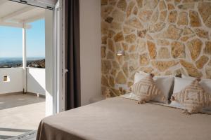 a bedroom with a stone wall and a bed with pillows at Villa THÉA - Private pool, Stunning Sea views in Plaka