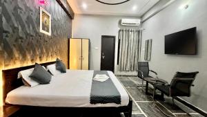 a bedroom with a bed and a chair and a tv at Hotel Madhav Inn in Lucknow