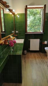 a green tiled bathroom with a sink and a window at La Caldara House in Manziana