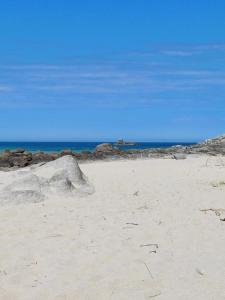 a sandy beach with a large rock and the ocean at Les coccinelles bretonnes in Plouescat