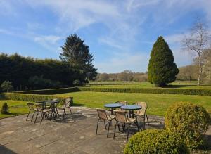 a patio with tables and chairs in a park at Yew Tree Retreat- Sunset Suite in Newbury