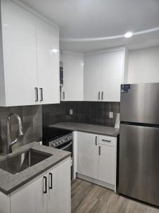 a kitchen with white cabinets and a stainless steel refrigerator at Modern 2-Bedroom Private Basement Apartment in Airdrie