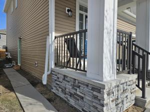 a porch with a chair on a house at Modern 2-Bedroom Private Basement Apartment in Airdrie
