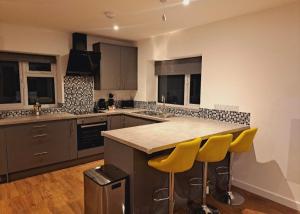a kitchen with a counter and yellow bar stools at Yew Tree Retreat- Sunset Suite in Newbury