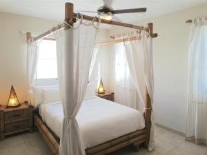 a bedroom with a canopy bed with white curtains at DELUXE OCEAN view VILLAS & Apartments with POOL - PLAYA LOS CORALES, BBQ, SPA in Punta Cana