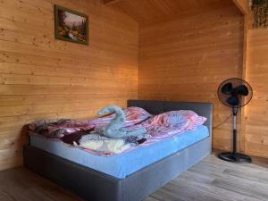 a bed in a wooden room with a fan at Domek Letniskowy in Iława