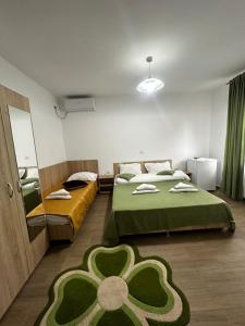 a bedroom with two beds and a green flower rug at Casa Enka in Tuzla