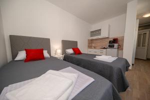 a bedroom with two beds with red pillows at Andrej Apartmani Rafailovici in Rafailovici