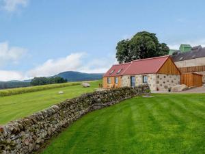 a barn and a stone wall next to a field at 1 Bed in Alness oc-83888 in Alness