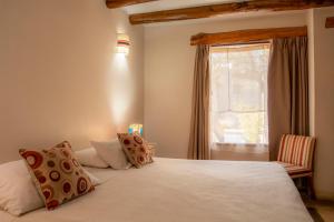 a bedroom with a bed with a window and a chair at KALLPA WARMI Hotel Panoramico in Tilcara +29 photos
