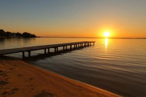 a pier on the water with the sunset in the background at Agroturystyka Biedrzycki in Nowe Guty