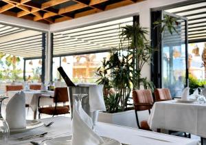 a restaurant with white tables and chairs and windows at OKEJ Hotel in Golem +25 photos