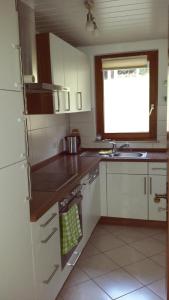 a kitchen with white cabinets and a sink and a window at Ferienwohnung Ringwald in Biederbach Baden-Württemberg