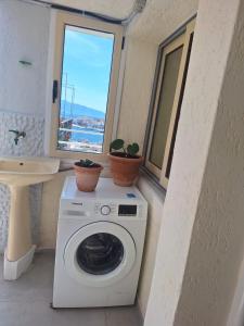 a washing machine in a bathroom with two potted plants at Sea & Relax Villa in Sarandë