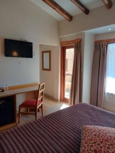 a bedroom with a bed and a chair and a television at KALLPA WARMI Hotel Panoramico in Tilcara