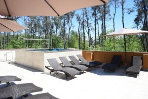a group of chairs and umbrellas next to a pool at Bellissimo Aparthotel Aqua in Shekhvetili
