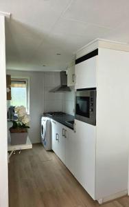 a kitchen with a stove and a washer and dryer at Robin's oak lodge in Epe +12 photos