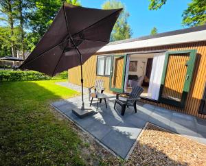 a patio with two chairs and an umbrella at Robin's oak lodge in Epe
