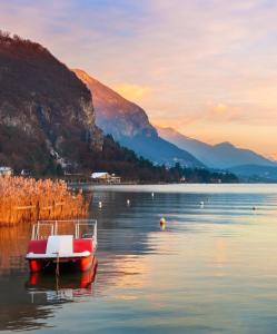 a boat in the water with mountains in the background at Studio moderne chaleureux et calme in Annecy +14 photos