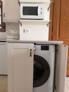 a kitchen with a washing machine and a microwave at Cozy Aegean Escape in Skopelos Town