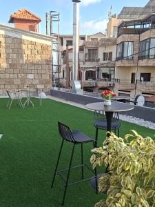 a patio with a table and chairs and green grass at Railway Studio 1 - Cozy Studio in Byblos - Central Location in Jbeil