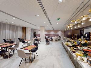 a restaurant with tables and chairs and a buffet at Mercure Bucharest City Center in Bucharest