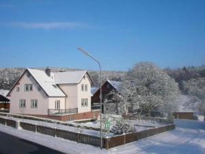 Une grande maison blanche avec de la neige au sol dans l'établissement Ferienhauser Siefertshof, à Mossautal