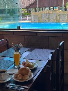 a table with a plate of food and orange juice at Hotel Maracanã in Pouso Alegre +23 photos