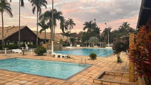 a large swimming pool in a resort with palm trees at Hotel Maracanã in Pouso Alegre