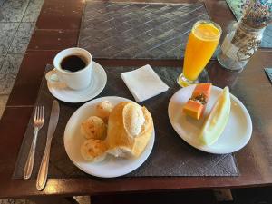 a table with two plates of breakfast foods and a cup of coffee at Hotel Maracanã in Pouso Alegre