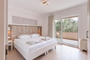 a white bedroom with a large bed and a large window at Resort Trcol in Novalja