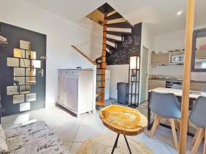 a living room with a staircase and a table and chairs at La coulée verte - superbe duplex climatisé - jardin - classé 3 étoiles in Luchon