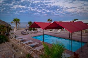 a pool with chairs and umbrellas next to the beach at Rancho Percebu Beach Studio 5 in San Felipe