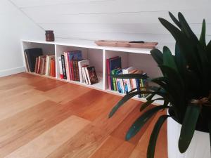 a book shelf filled with books next to a potted plant at Appartement du Fournil in Bréal-sous-Montfort