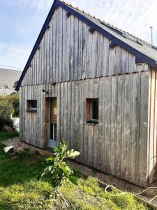 an old wooden barn with a door and windows at Appartement du Fournil in Bréal-sous-Montfort