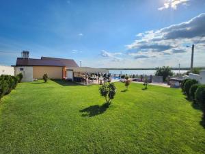 ein grüner Garten mit einem Haus und einem See in der Unterkunft CasaMari in Corbu