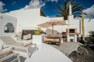 a white house with a patio with an umbrella at Villa Lore by Villalize in Teguise