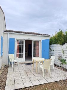 a patio with chairs and a table and a house at La petite Lotie in Saint-Denis-dʼOléron