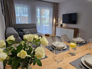 a living room with a table with flowers and wine glasses at Blue Wave Pobierowo in Pobierowo