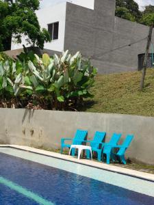 four blue chairs and a table next to a pool at La Terraza in Villeta