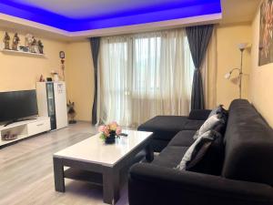 a living room with a black couch and a table at Chic Peak Apartment - Kalinderu Slope & View in Buşteni