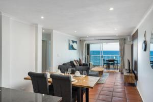 a dining room and living room with a table and chairs at Rustic Beachfront Apt! Shared Pool! in Umdloti