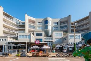a large building with tables and umbrellas in front of it at Rustic Beachfront Apt! Shared Pool! in Umdloti