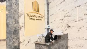 a man sitting on a ledge in front of a building at Zafran Smart Luxury Suite in Dushanbe