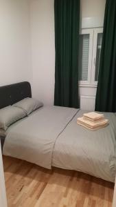 a bed in a room with green curtains at Apartman Sanja Ledine in Ledine