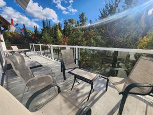 a deck with chairs and tables on a balcony at Maison Conteneur d'Expedition in Amos