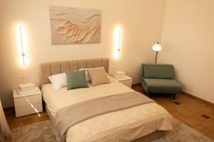 a bedroom with a bed and a green chair at Central Apartment Chortkiv in Chortkiv